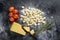 Uncooked homemade potato gnocchi with ingredients for cooking pasta. Black background. Top view