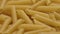 Uncooked Italian wheat penne pasta close-up.