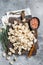 Uncooked Manti Dumpling on wooden board with herbs, raw food. Gray background. Top view