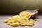Uncooked pasta, farfalle in scoop on a rustic wooden table.