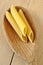 Uncooked penne pasta on a wooden spoon