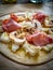 Uncooked pizza with artichokes, champignons, ham and mozzarella on wooden background