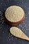 Uncooked quinoa in a brown wooden bowl and spoon on dark stone background. Dry cereal grains, cooking ingredient