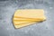 Uncooked Raclette Swiss cheese slices. Gray background. Top view