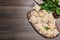 Uncooked ravioli, basil and peppercorns on wooden table, flat lay. Space for text