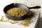 Uncooked, raw freekeh or firik, roasted wheat grain, in metal pan on white rustic table background