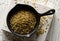 Uncooked, raw freekeh or firik, roasted wheat grain, in metal pan on white rustic table background top view