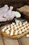 Uncooked raw homemade dumplings on a board with flour on a dark wooden background