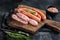 Uncooked Raw sausages Chorizo and Bratwurst with spices on wooden board. Black background. Top View