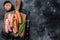 Uncooked Raw sausages Chorizo and Bratwurst with spices on wooden board. Black background. Top View. Copy space