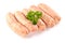 Uncooked sausages with a leaf of parsley, on white background