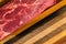 Uncooked steak sitting on wooden cutting board