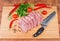 Uncooked steaks of pork neck on cutting board with knife