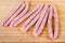 Uncooked thin long pork sausages on the wooden cutting board