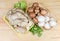 Uncooked various cultivated mushrooms and greens on wooden rustic table