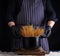 Uncooked yellow long spaghetti in a black metal pan and a chef in a striped apron