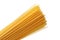 Uncooked yellow wheat spaghetti noodles on white background