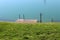 Uncut grass covered river bank with small flooded concrete pier with metal steps