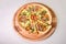 Uncut meat pizza on round wooden cutting board isolated on background. Slice of meat pizza with melted cheese
