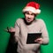 Undecided young santa man holding a tablet pad