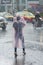 Undefined girl in raincoat crossing street during tropical storm