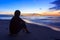 Undefined traveler sitting at the beach in sunrise time