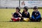 Under 12 rugby players sitting on the pitch waiting for the next coach\'s call