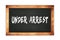 UNDER  ARREST text written on wooden frame school blackboard