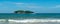 Under the blue sky and white clouds, the waves wash on the beach, and the small island in the distance