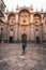 Under a blue umbrella, a person poses by Granada\\\'s cathedral