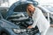 Under the car hood. Woman in formal clothes is indoors in the autosalon