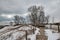 Under a cloudy Winter sky, a boardwalk passes through snow-covered dunes