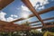 Under construction garden pergola with wooden structure in sunny backyard surrounded by tropical plants