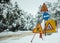 Under construction signs in snow. Snowy road and forest background.