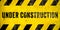 Under construction warning sign text with yellow black stripes painted over concrete wall cement facade texture background banner