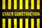 Under construction warning sign with yellow and black stripes painted over cracked concrete wall coarse texture background