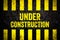 Under construction warning sign with yellow and black stripes painted over cracked concrete wall weathered texture background