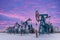Under the purple-blue sky with clouds seven Oil pumpjack winter working. Oil rig energy industrial machine for petroleum in the