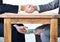 Under-the-table transactions.... Cropped shot of two businessmen shaking hands while money passes hands under a table.