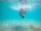 Under water photo of a woman in bikini diving in turquoise sea water