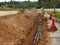 Underground utility and services pipe laid by workers in the trenches at the construction site.