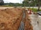 Underground utility and services pipe laid by workers in the trenches at the construction site.