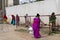 Underprivileged women in sarees stand in a ilne following the social distancing norms to collect food rations at a