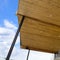 Underside of roof with brown wooden planks and round ceiling lights against sky