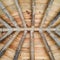 Underside of a wooden shingled roof supported by bamboo and concrete structure