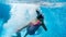 Underwater image of two teenage girl jumping and diving in swimming pool at gym