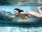 Underwater photo of aisan woman in bikini diving in the swimming pool with transparent glass wall. infinity pool edge on tropical
