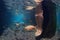Underwater picture of female legs and koi fishes in pond