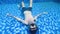 Underwater scene of a man lying at the bottom of the pool making bubble rings.