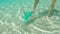 Underwater shot of a man that collects plastic bags in the beautiful turquoise sea. Paradise beach pollution. The